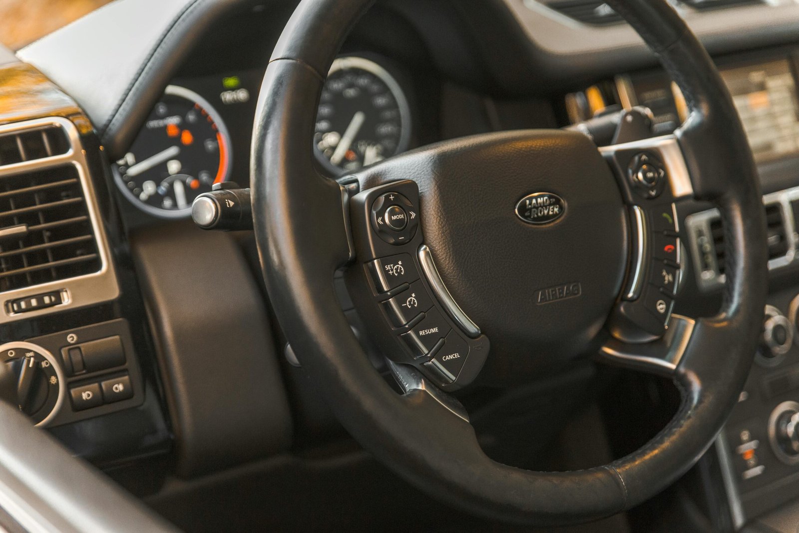 Close-up view of a luxurious Land Rover car interior highlighting the steering wheel and dashboard.